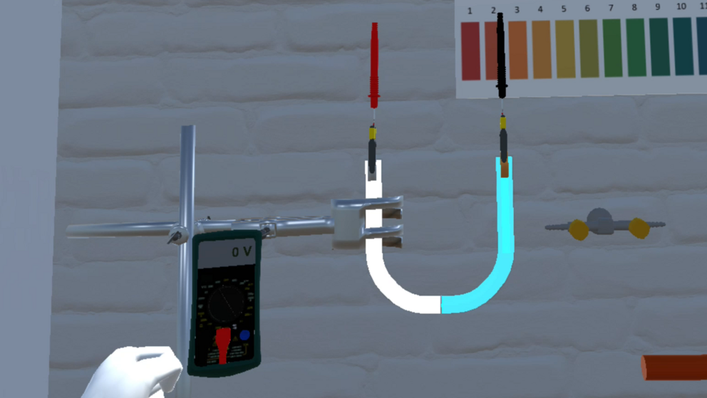 A galvanic cell realized in a u-tube inside the VirtuChemLab. Next to it is a multimeter showing a coltage reading.